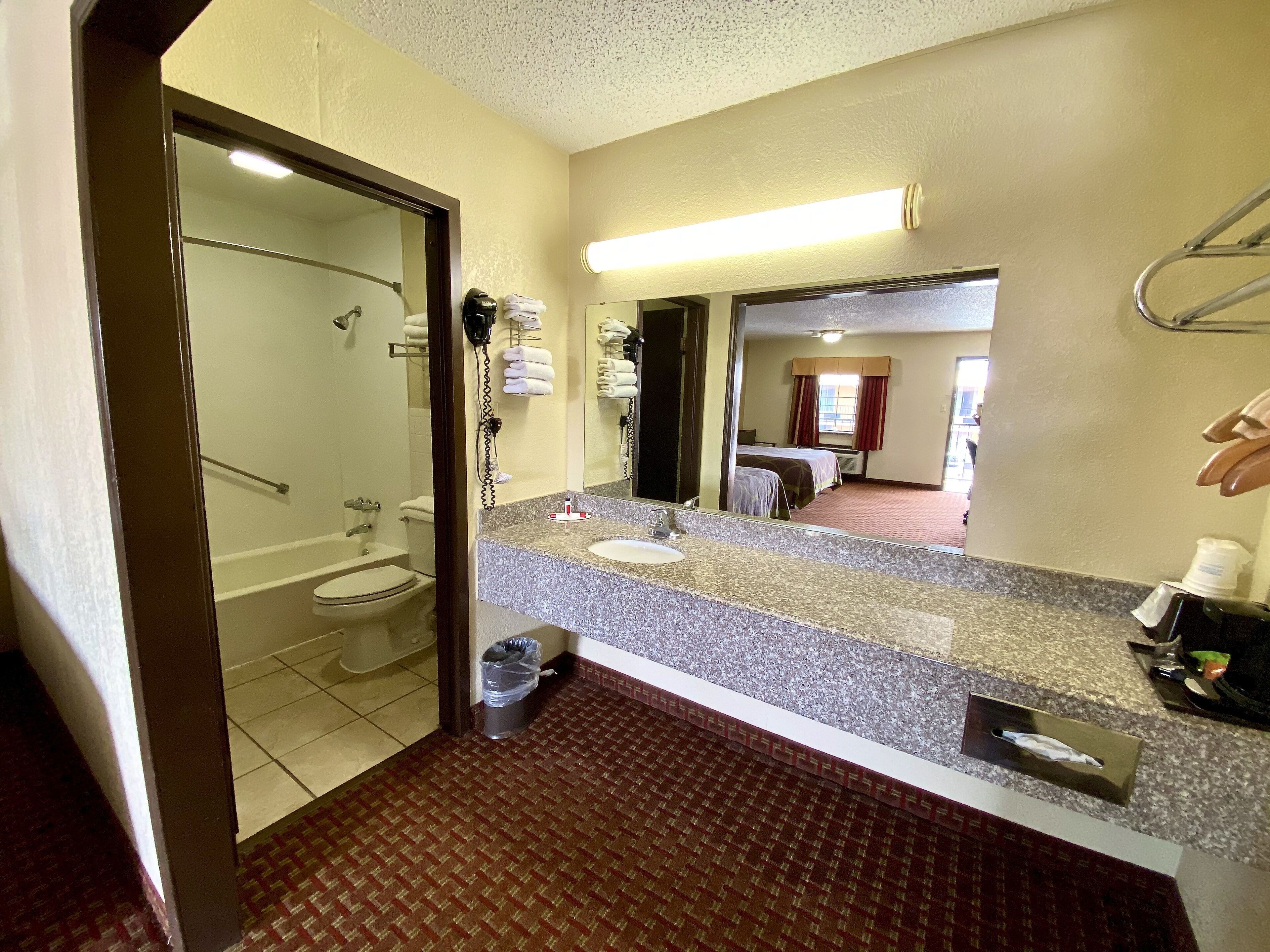 Ein Hotelbad mit Dusche, Toilette, Waschbecken und einem großen Spiegel.