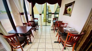 A dining area with wooden tables and chairs, a tiled floor, and a view of the outside through large windows. - Super 8 by Wyndham Shawnee (Shawnee)