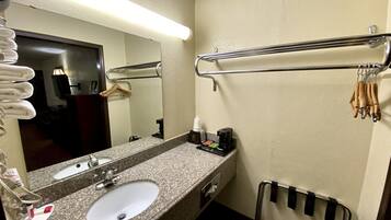 A hotel bathroom with a granite countertop sink, a mirror, a towel rack, and a hand dryer.