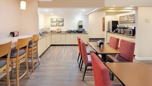 Comedor moderno de hotel con sillas y mesas de madera, una cafetera y un microondas.