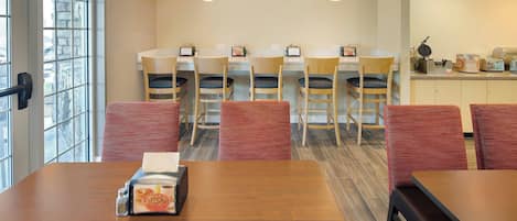 A dining area with a wooden table, red chairs, and a kitchen counter with a waffle maker.