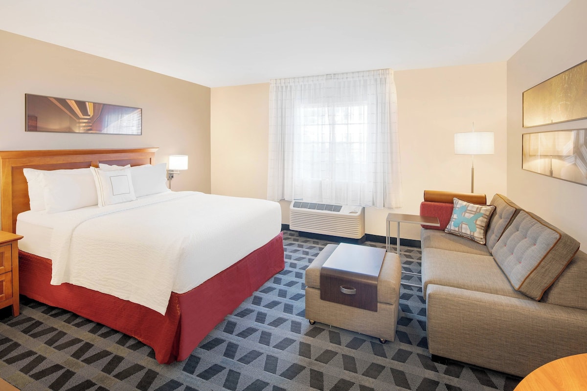 Une chambre d’hôtel avec un grand lit, un canapé, une petite table et une fenêtre avec des rideaux.