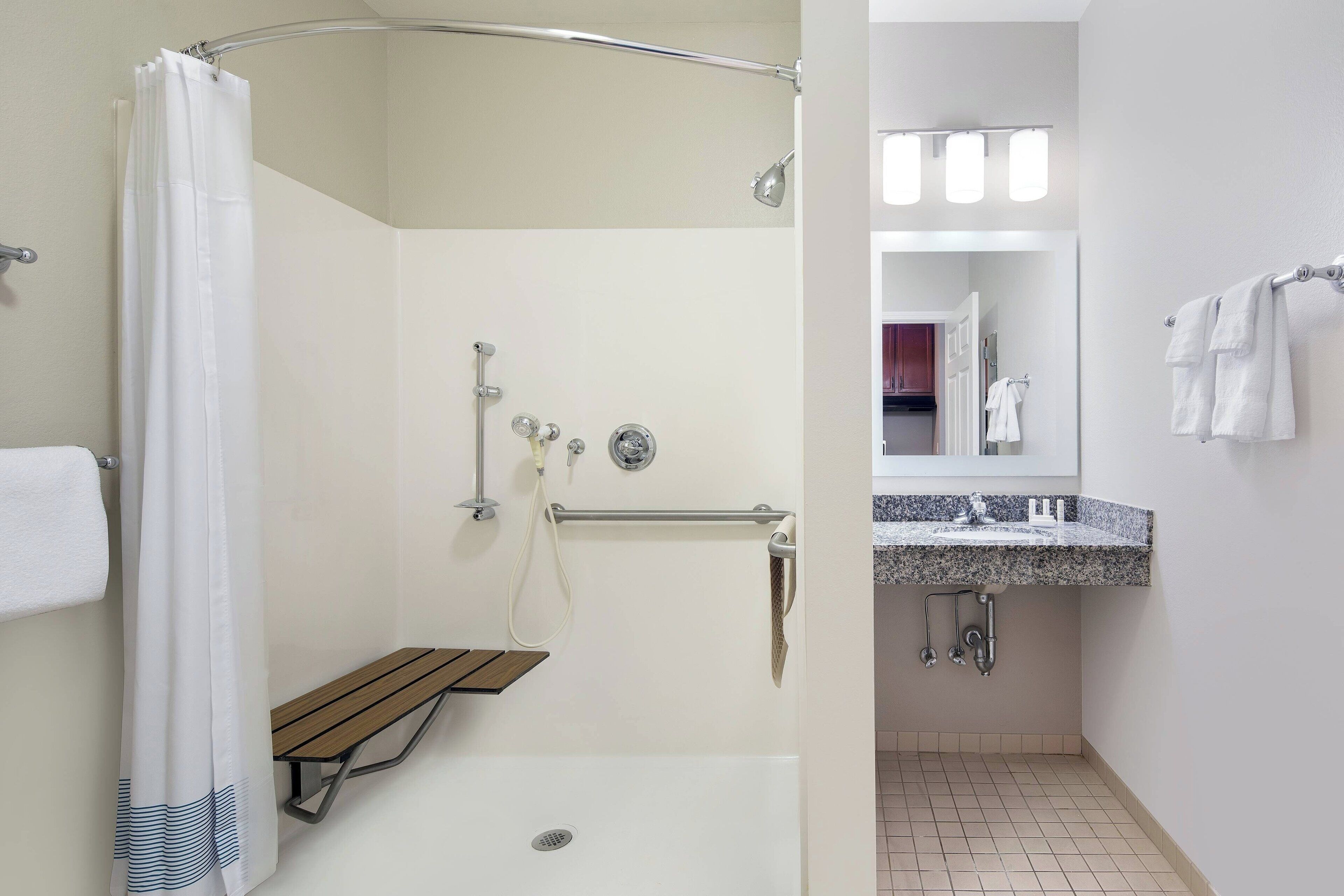 A modern bathroom with a shower, a vanity with a sink, and a mirror.