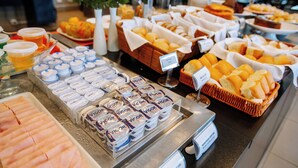 Un buffet proposant une variété d’aliments, notamment des pâtisseries, du pain et des pots de yaourt.