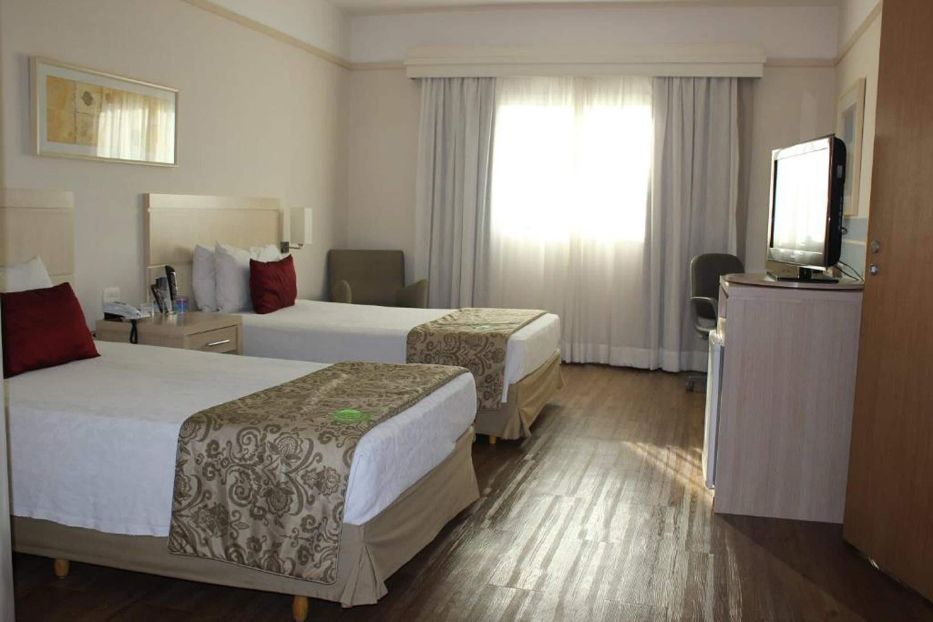 Una habitación de hotel con dos camas, un escritorio, un televisor y una silla.