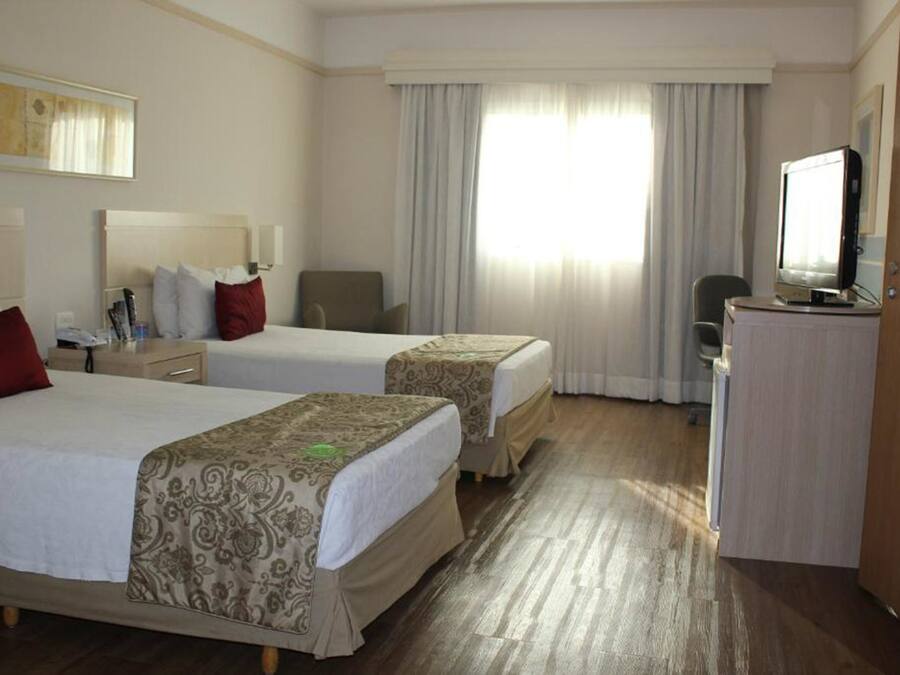 Una habitación de hotel con dos camas, un escritorio, un televisor y una silla.