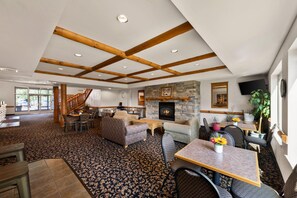 A spacious living area with a fireplace, comfortable seating, and a staircase leading to another level.