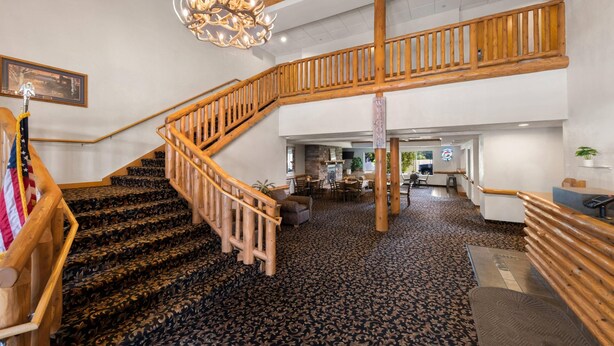 Un vestíbulo de hotel con una escalera monumental, un candelabro y una recepción.
