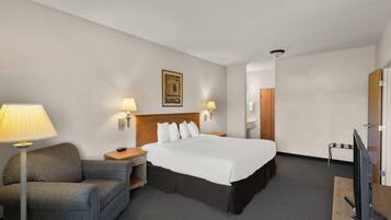 A hotel room with a bed, two bedside lamps, a desk with a computer, a chair, and a television.