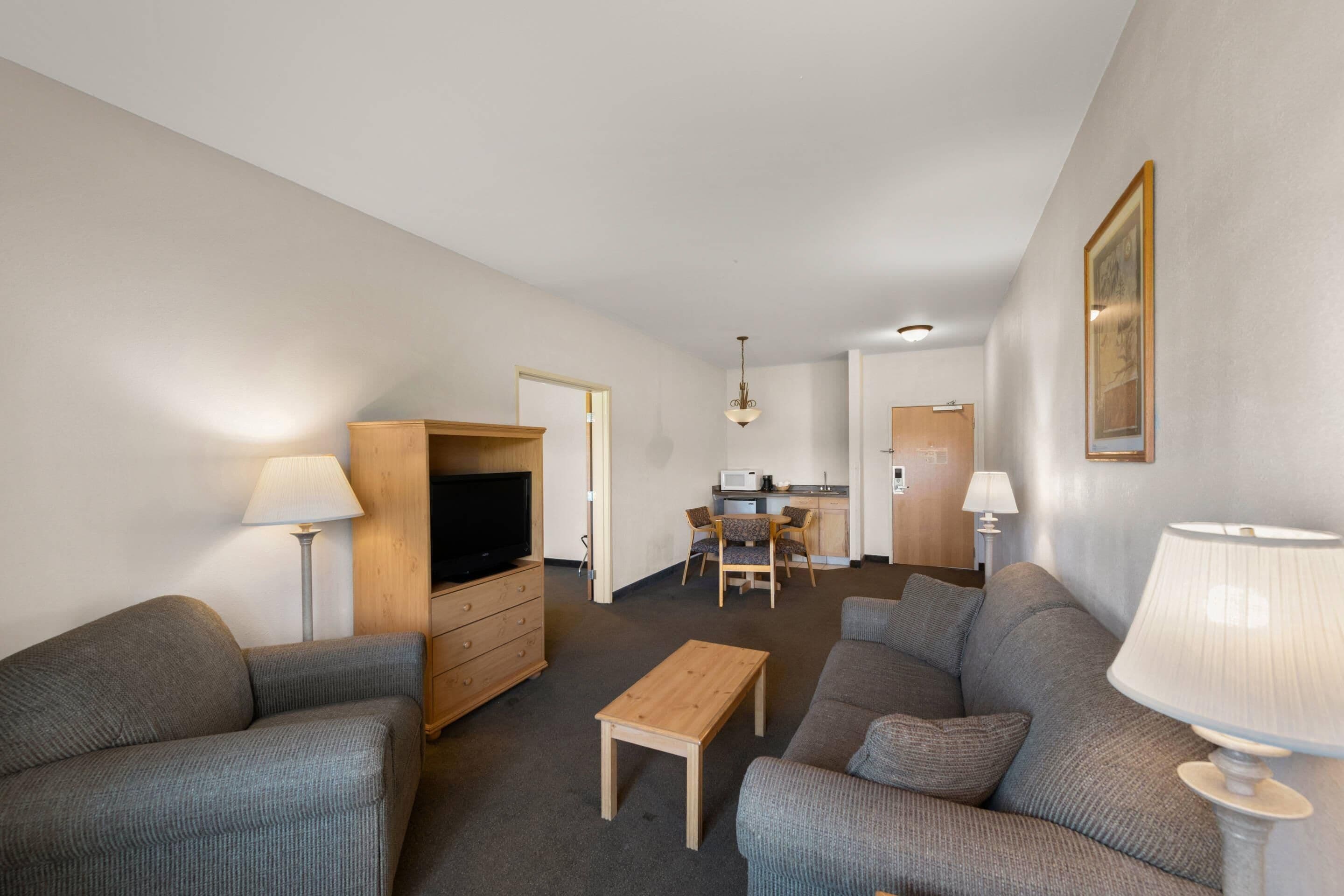 A modern living room with a sofa, a coffee table, a TV, and a dining area with chairs and a table.