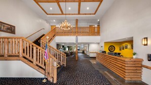 Un hall espacioso con una escalera de madera, una araña y una mesa de recepción.