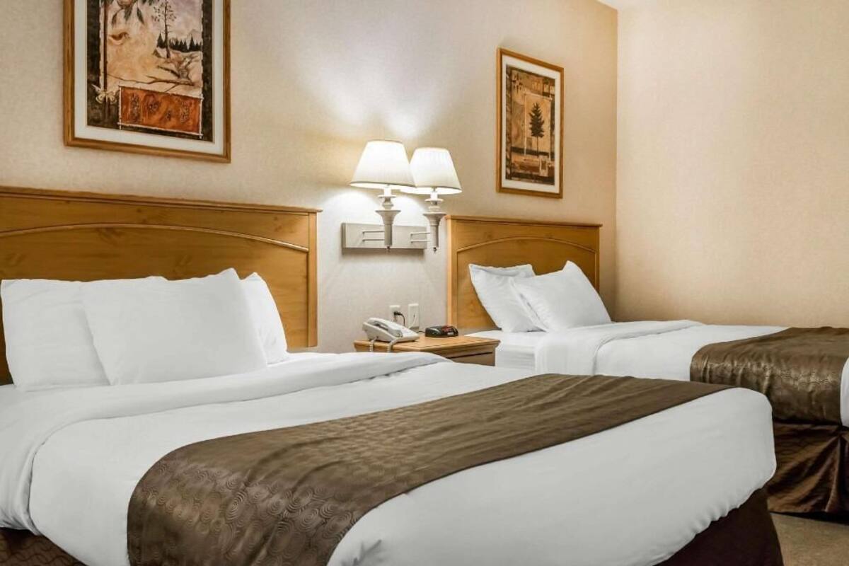 Habitación de hotel con dos camas, una mesita de noche con teléfono y lámparas de pared.