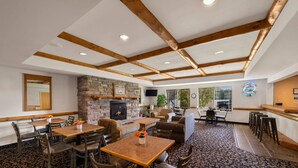 Amplio espacio interior con vigas de madera, chimenea de piedra y diferentes opciones de mobiliario, incluyendo mesas y sillas.