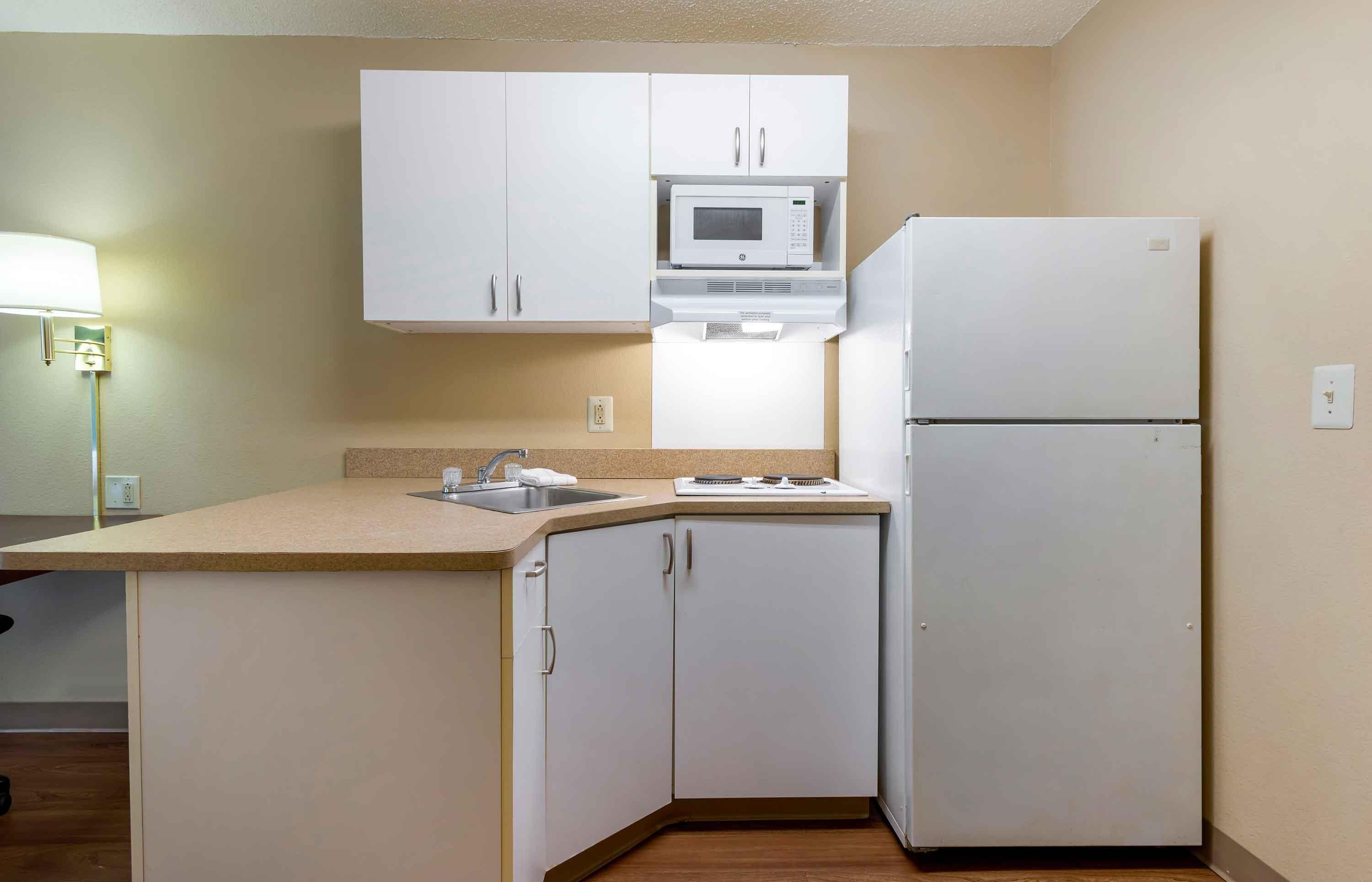 Une petite cuisine équipée avec des meubles blancs, un four à micro-ondes et un réfrigérateur.