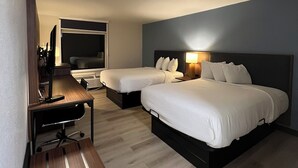 Een hotelkamer met twee bedden, een bureau, een stoel, een televisie en een lamp.