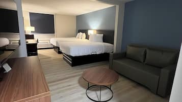 A hotel room with a bed, a sofa, a desk, and a round table.
