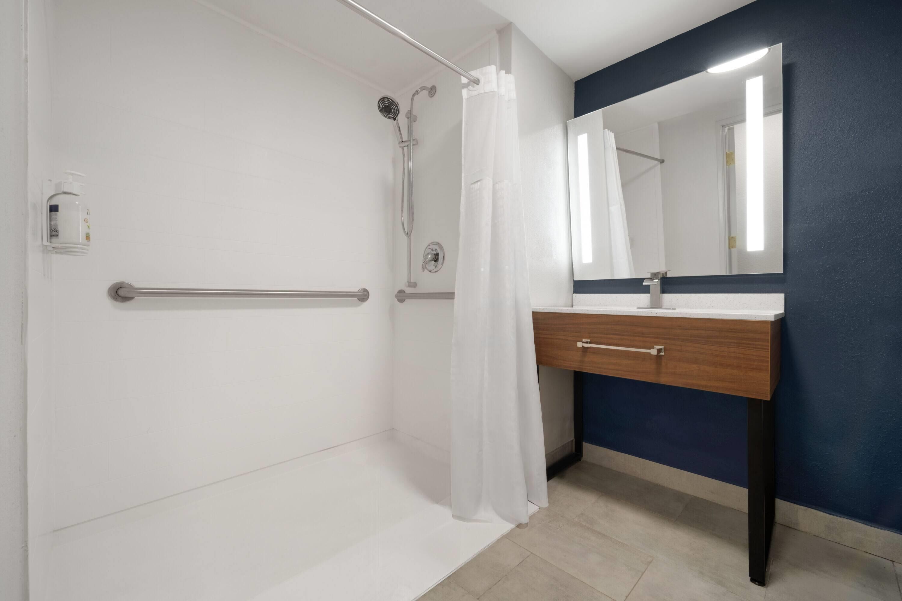 A bathroom with a shower, a sink, and a mirror.