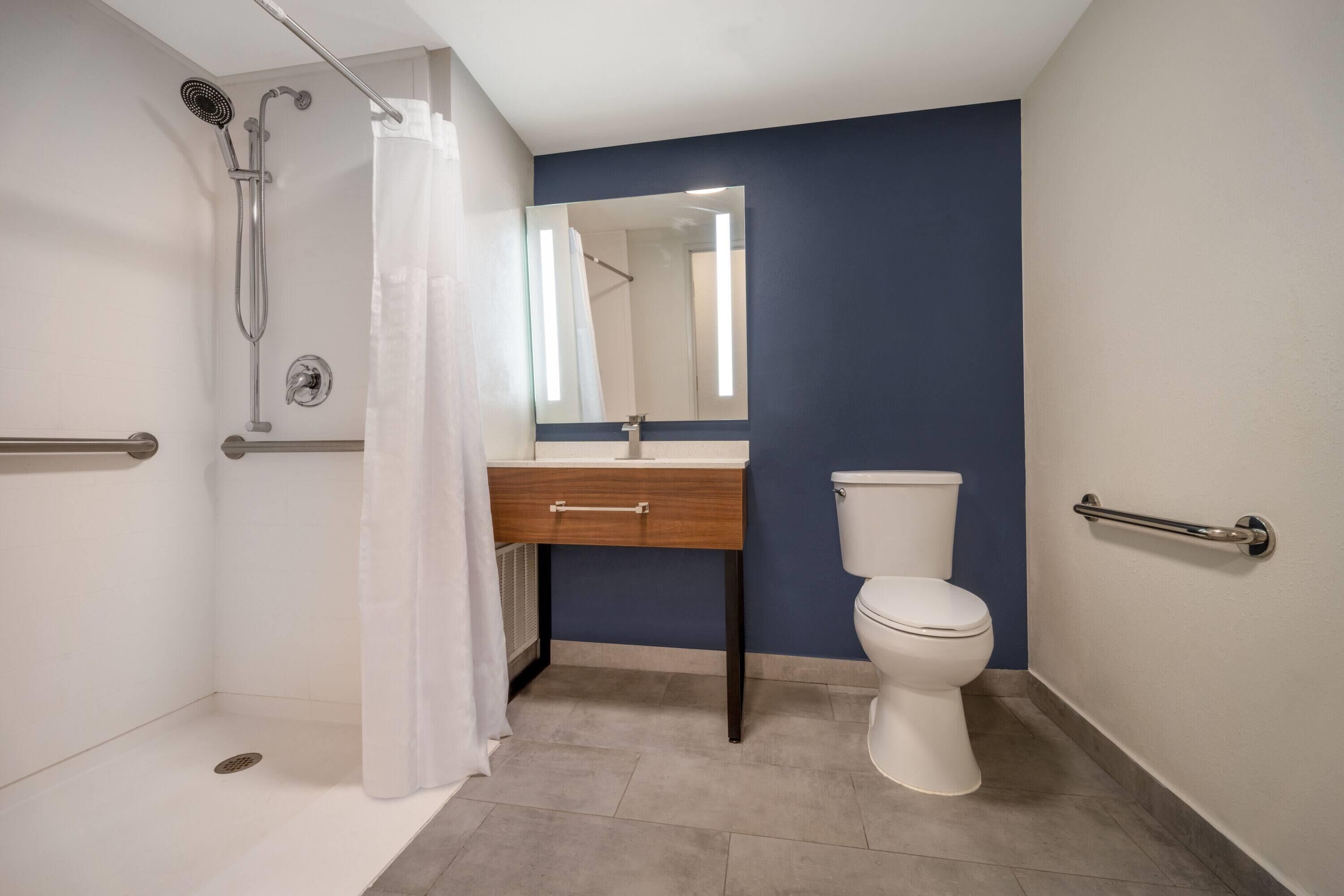 Une salle de bain avec douche, toilettes et lavabo.