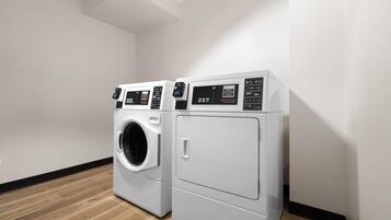 A laundry room with two white front-loading washing machines and a dryer.