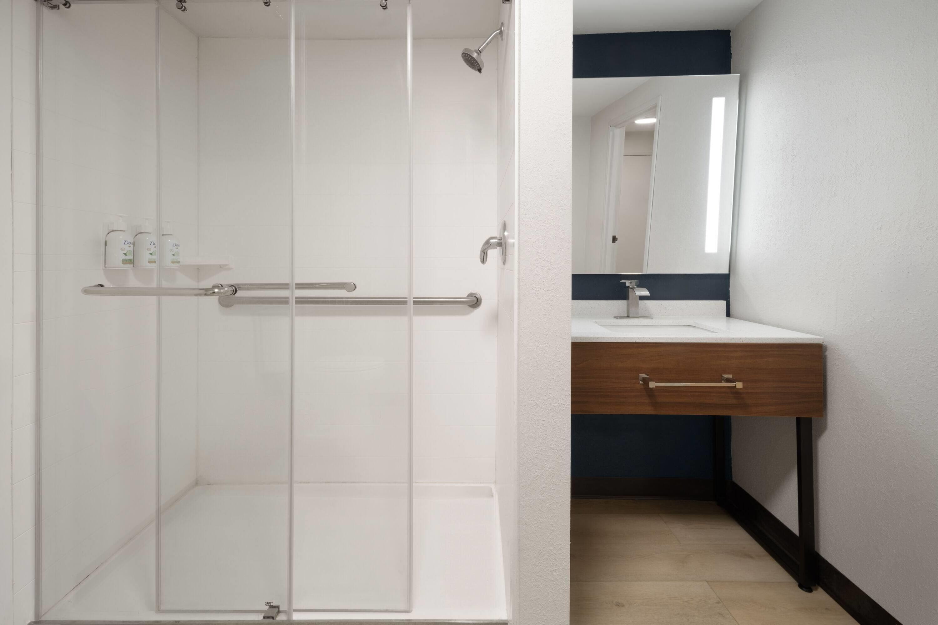 A bathroom with a shower, a sink, and a mirror.