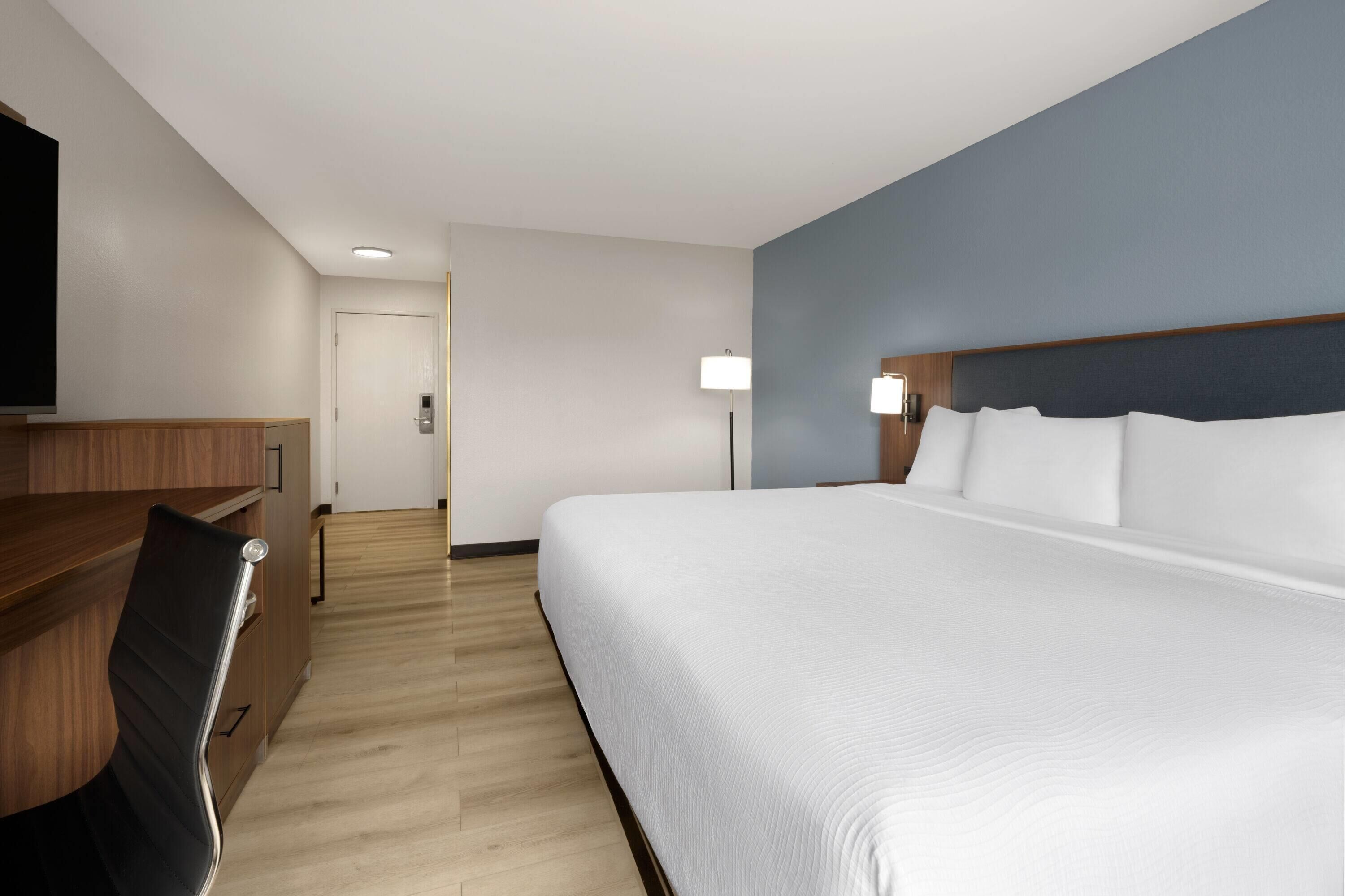 Una habitación de hotel con una cama grande, un escritorio y una silla.