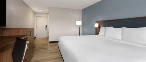 A hotel room with a large bed, a desk, and a chair.