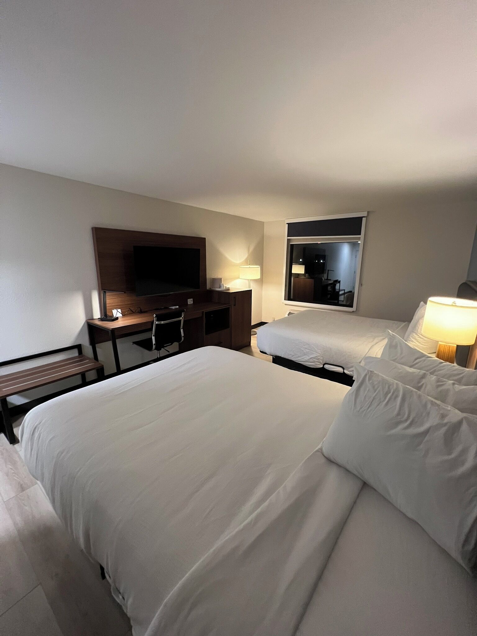 Une chambre d’hôtel avec un grand lit, un bureau avec une télévision et une fenêtre.