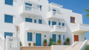 Un bâtiment blanc agrémenté de touches de bleu, doté de nombreux balcons et orné de plantes en pot.