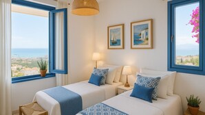 Une chambre d’hôtel avec deux lits, une vue sur la mer et deux tableaux encadrés accrochés au mur.