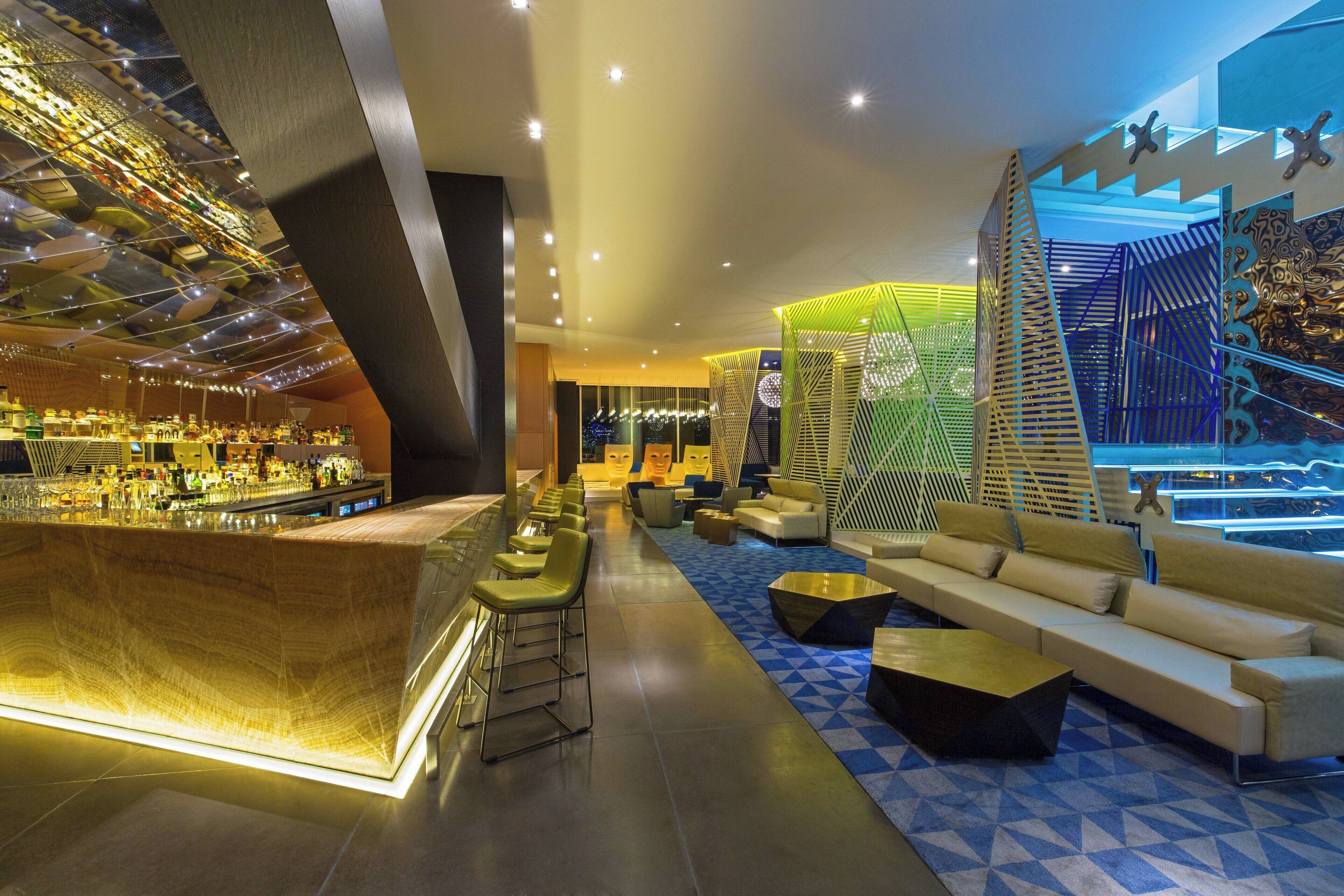 Un moderno hall de hotel con zona de bar, disposición de asientos y suelo estampado.