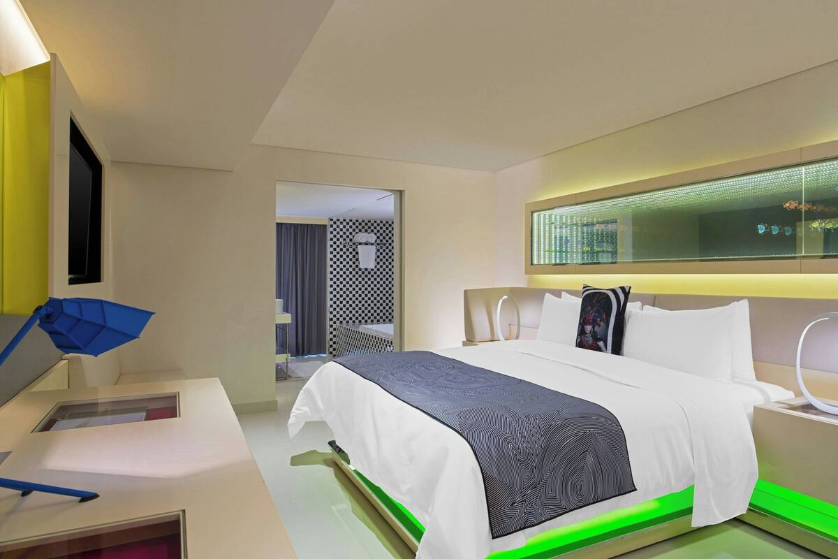 Una habitación de hotel moderna con una cama bien hecha, un escritorio con una lámpara y un ventanal con vistas.