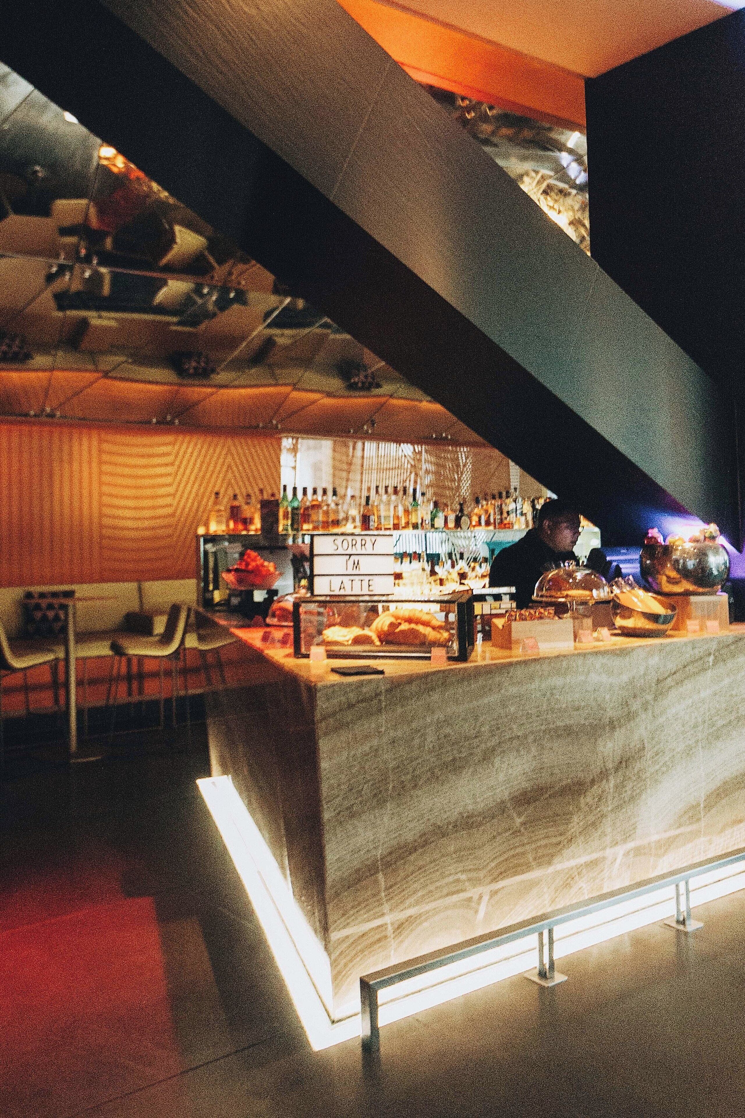 Zona de bar con mostrador, sillas y un cartel que dice 'SORRY I'M LATTE'.