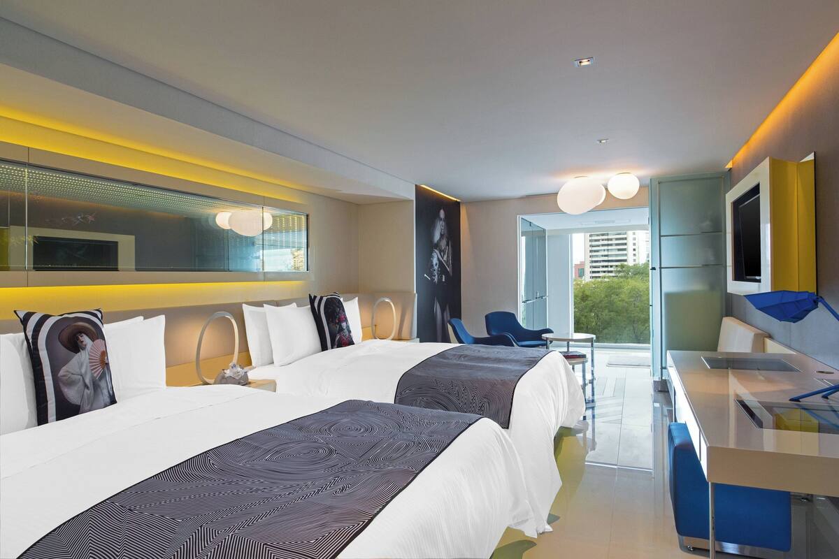Una habitación de hotel moderna con dos camas, un escritorio y una zona de estar.