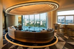 Un salón moderno con un sofá curvo, una mesa de vidrio y vistas a la ciudad.