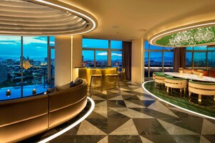 Un moderno hall de hotel con una zona de estar curva, un bar y amplias ventanas con vistas a la ciudad.