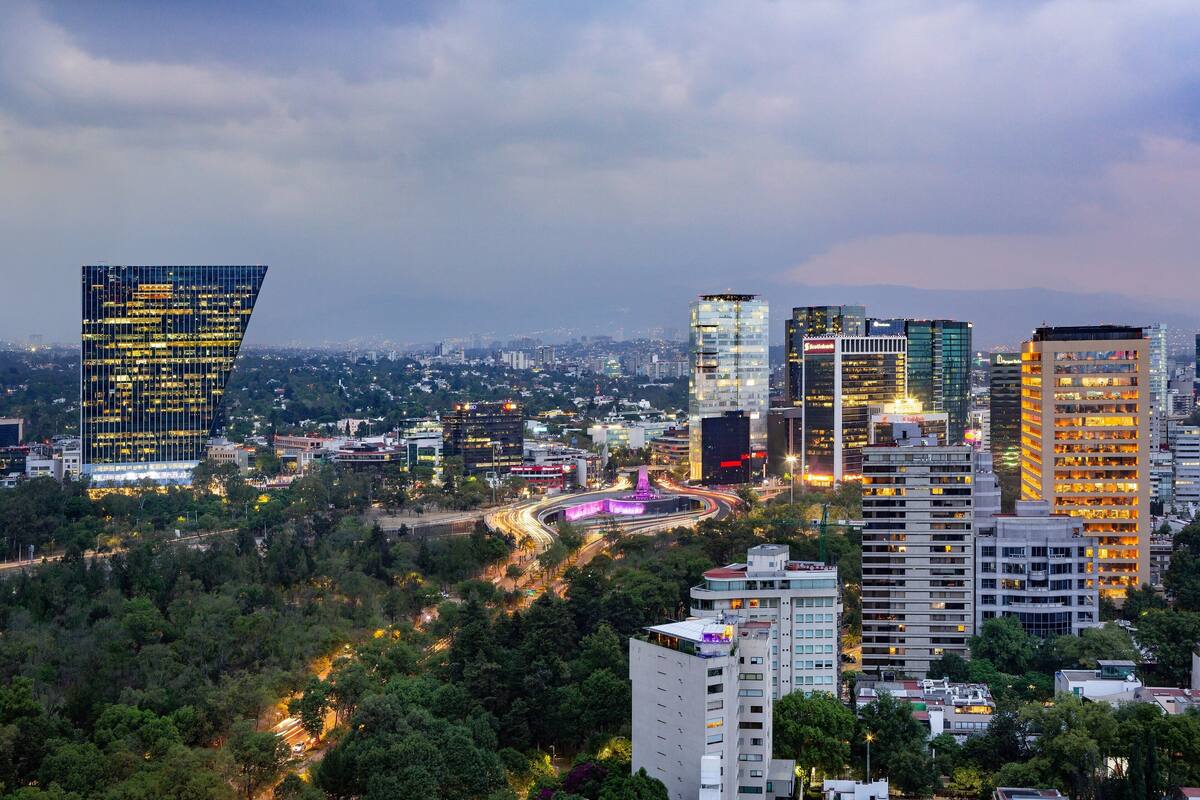 Un paisaje urbano con modernos rascacielos, una autopista y zonas verdes circundantes.