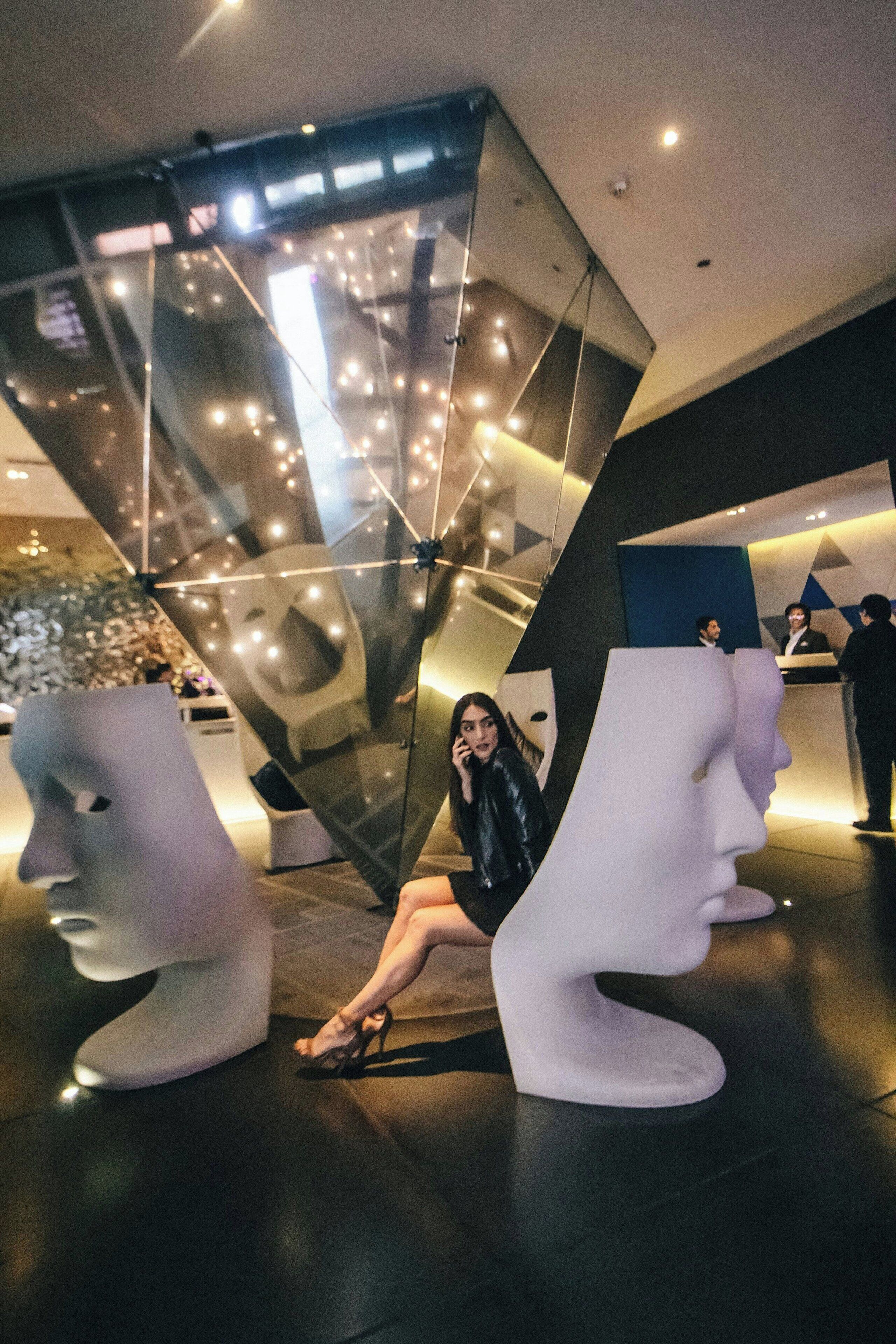 A modern lobby with abstract sculptures, a reception desk, and a staircase.