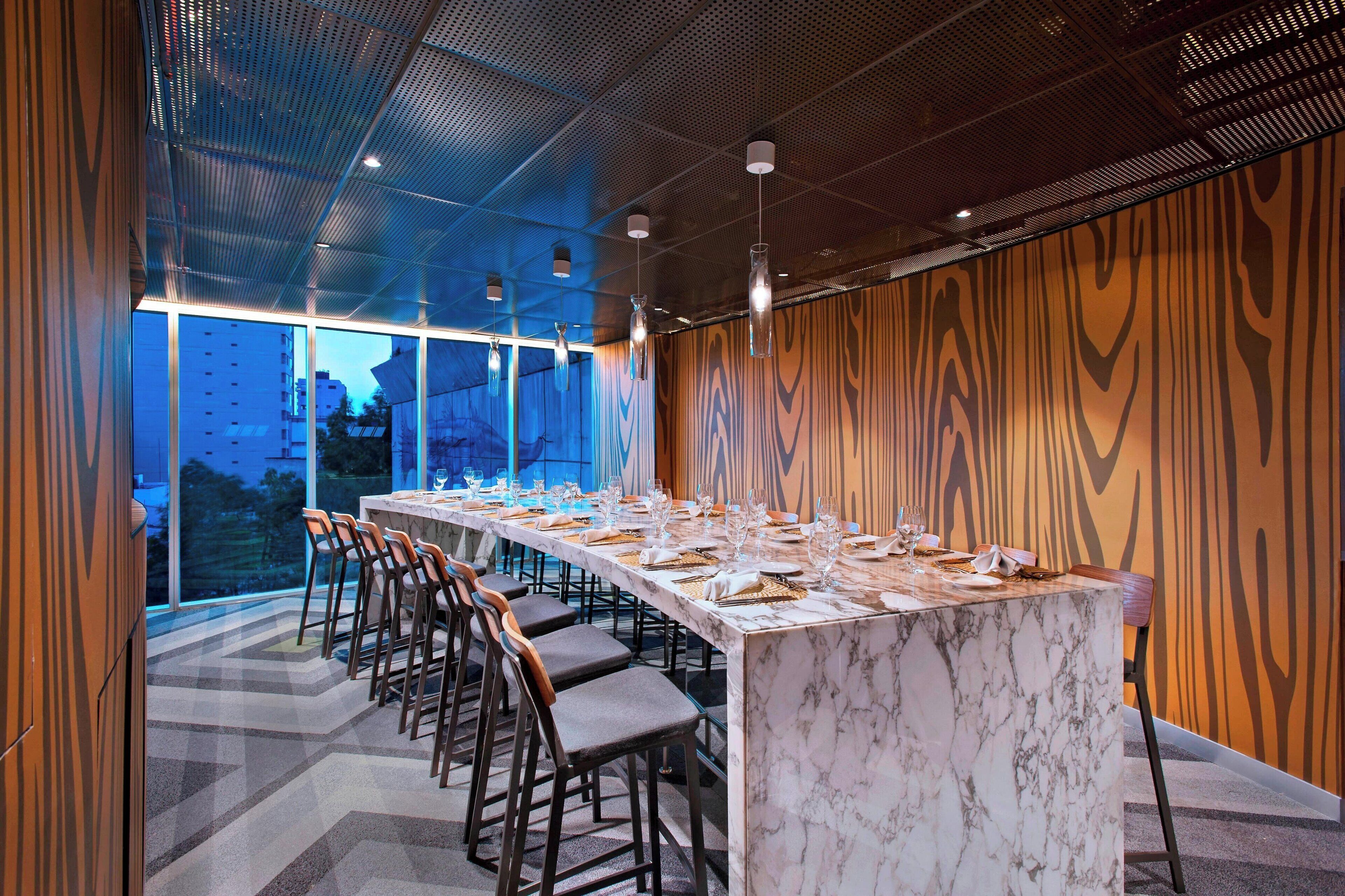 A modern conference room with a long table set for a meeting, equipped with chairs and a marble table.