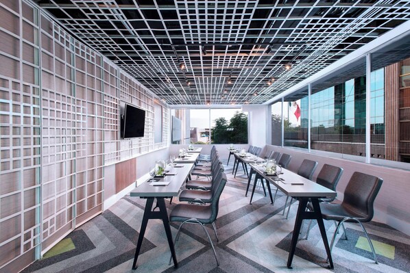 A conference room with a grid-patterned ceiling, long tables with chairs, and large windows offering a view of the outside. - W Mexico City (Mexico City)