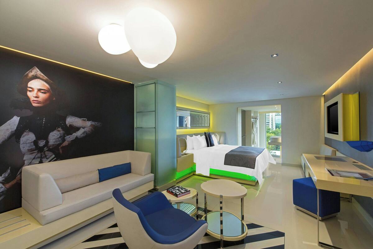 Una habitación de hotel moderna con una cama grande, un sofá, un escritorio y una silla.