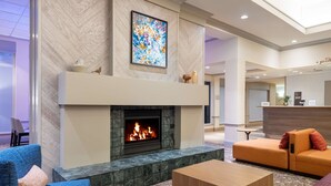 A modern lobby with a fireplace, seating area, and a reception desk. - Hilton Garden Inn Montgomery East (Montgomery)