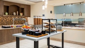 A buffet setup with various food items and condiments. - Hilton Garden Inn Montgomery East (Montgomery)