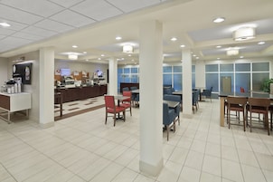 A spacious lobby with multiple seating areas, a reception desk, and a coffee station.
