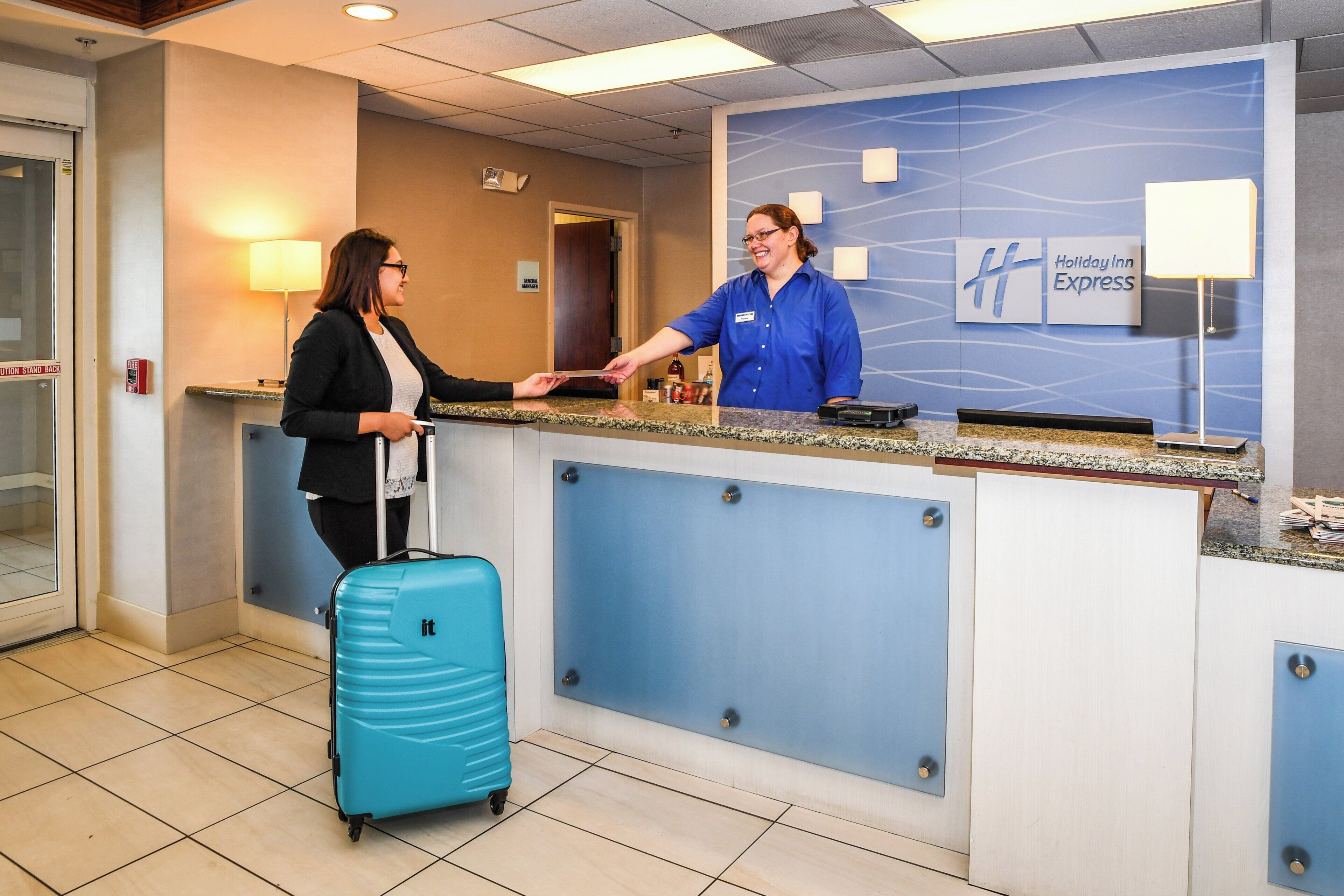 A hotel reception desk with a blue wall, a name tag, and a sign for Holiday Inn Express.