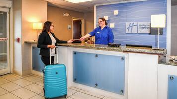 A hotel reception desk with a blue wall, a name tag, and a sign for Holiday Inn Express.