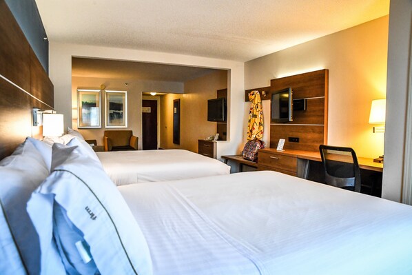 Een hotelkamer met twee bedden, een bureau met stoel, een televisie en een spiegel.
