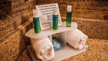 A hotel bathroom with toiletries on a tray, including bottles and towels.