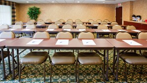 A conference room with rows of tables and chairs, a potted plant, and an exit door. - Holiday Inn Express Hotel & Suites Concord by IHG (Kannapolis)