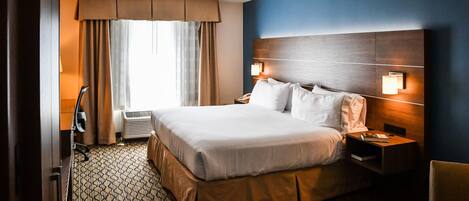 A hotel room with a large bed, two bedside tables, a desk, and a chair.