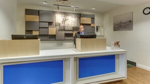 Un comptoir d’accueil au design moderne, une horloge au mur et un tableau encadré.